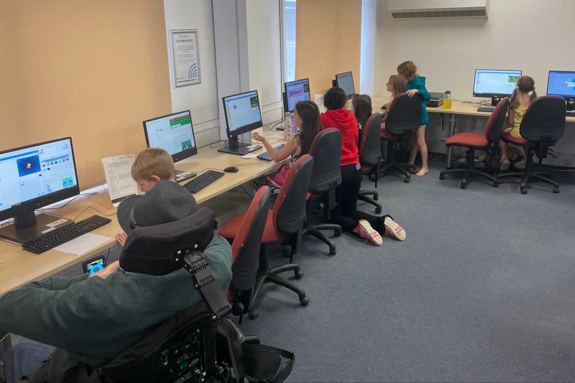 Children working on coding projects, at a row of computers